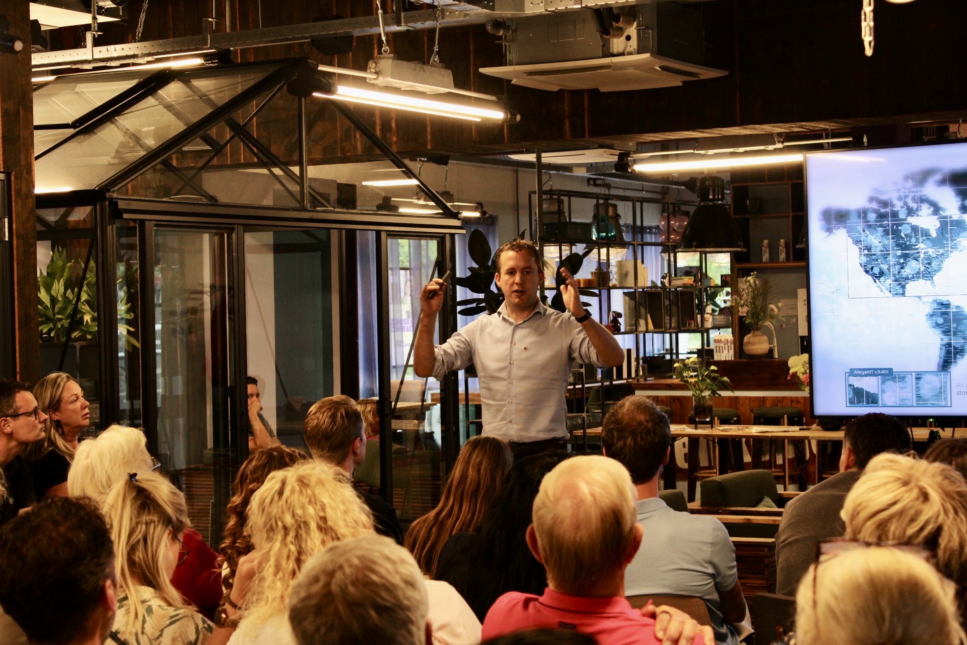 Tom geeft een presentatie voor een groot publiek